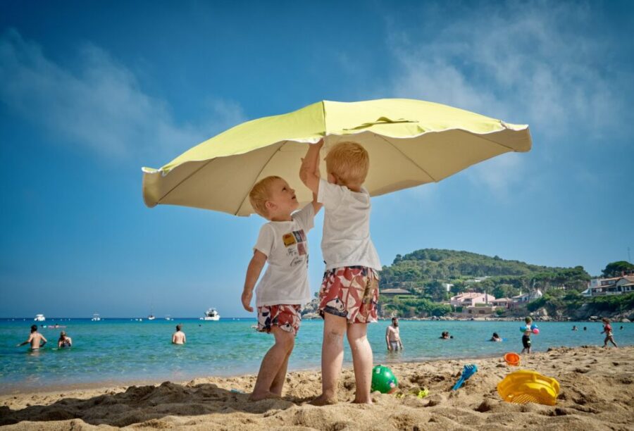 Kids at the beach with an umbrella.